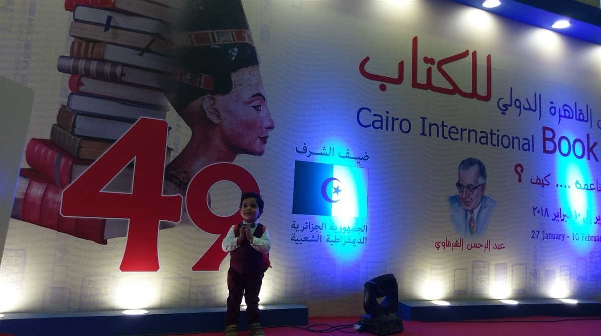 أحد أبنائه خلال مشاركة والده في معرض الكتاب 