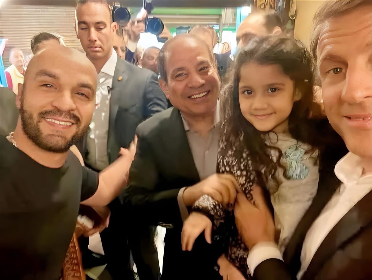 الرئيس الفرنسي يحمل طفلة مصرية بخان الخليلي