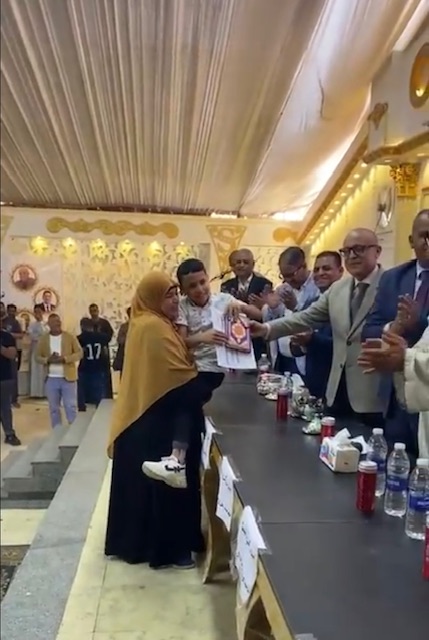 حملت إبنها على كتفها لتسلم تكريمة