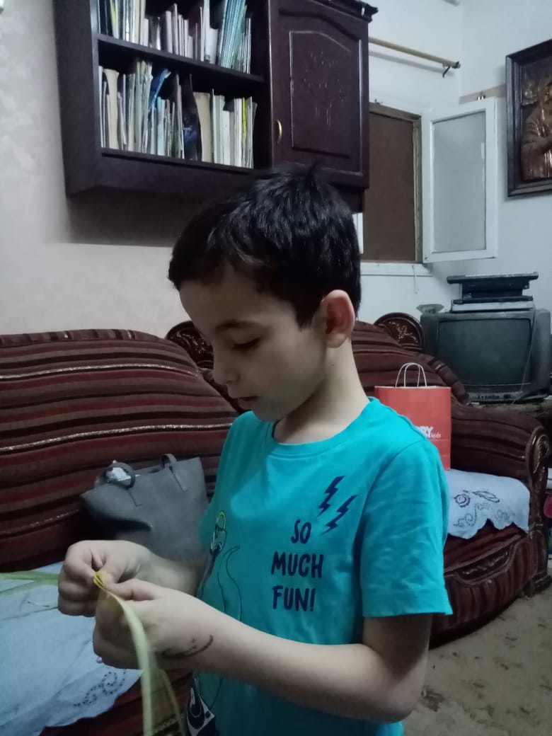 طفل يصنع أشكالًا من السعف