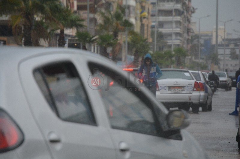 شاب يحتمي بالملابس الشتوية من الأمطار 