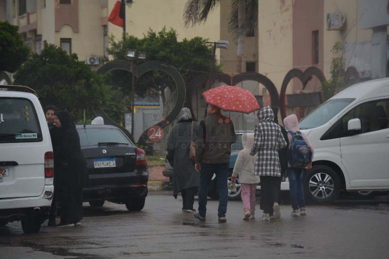 اسرة تحتمي بـ شمسية من الأمطار 1