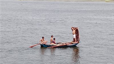 بالملابس الداخلية.. مواطن يهرب إلى وسط النيل على فلوكة مع أبنائه من شدة الحر بقنا│صور