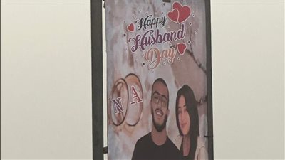 لوحة تحمل صورة لـ زوجين أعلى كوبري 15 مايو تثير إعجاب المارة 
