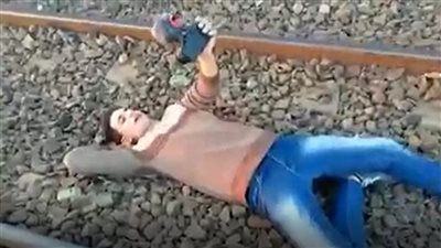 واقعة جديدة.. شاب يتحدى أصدقائه  بالنوم أسفل قطار السكة الحديد لجذب المشاهدين (فيديو)