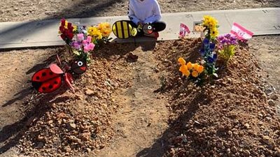 أم تنشر صورة ابنتها وهي تجلس بجانب قبور أشقائها الثلاثة لتتحدث معهم