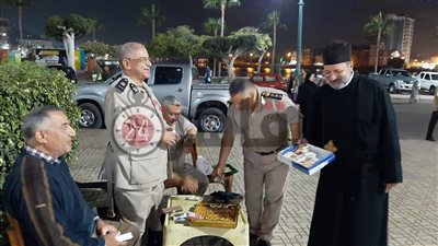 كاهن كنيسة الروم الأرثوذوكس يوزع حلويات المولد على المواطنين بشوارع دمياط (صور)