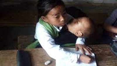 أم صغيرة.. طفلة هندية تحمل أخيها الرضيع خلال حضورها إلى المدرسة