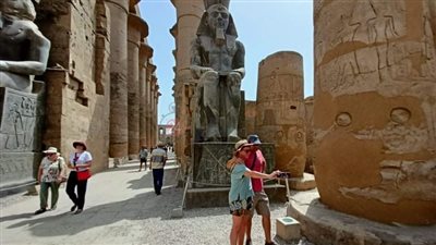 مطلعش نايم.. سياح يلتقطون الصور التذكارية مع تمثال رمسيس الثاني بمعبد الأقصر | صور